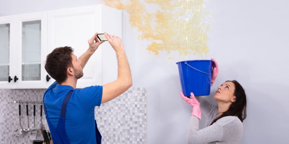 Homeowner documenting water damage in their home for an insurance claim with photos and notes