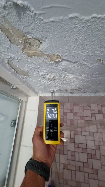 Professional restoration technician using a moisture metre to assess water damage on a wall