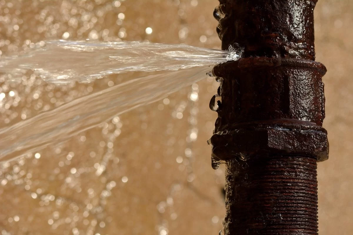 Rusty burst copper pipe leaking water inside a wall cavity causing water damage